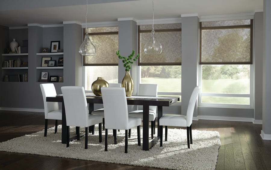 A dining room room featuring three windows with automated window shades lowered halfway on all of them.