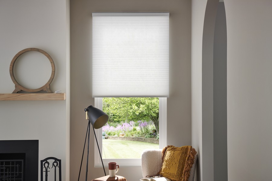 Honeycomb Lutron shades on a narrow window in front of a lamp and chair