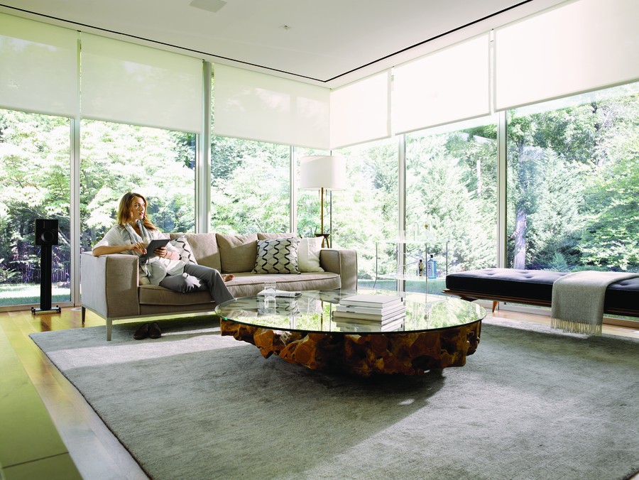 Woman lounging in a modern living room using a tablet to select music to hear on a whole-home audio system.