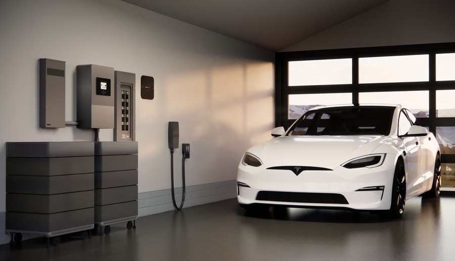 A luxury white electric vehicle parked in a modern garage equipped with a Savant Power home energy management system, including battery storage units and an EV charging station.