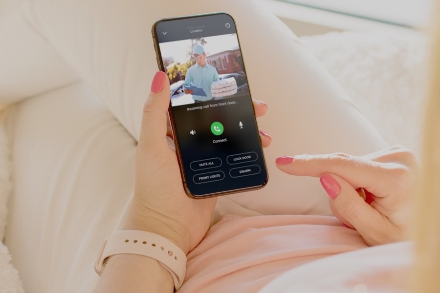 person holding a smartphone showing a surveillance camera feed.